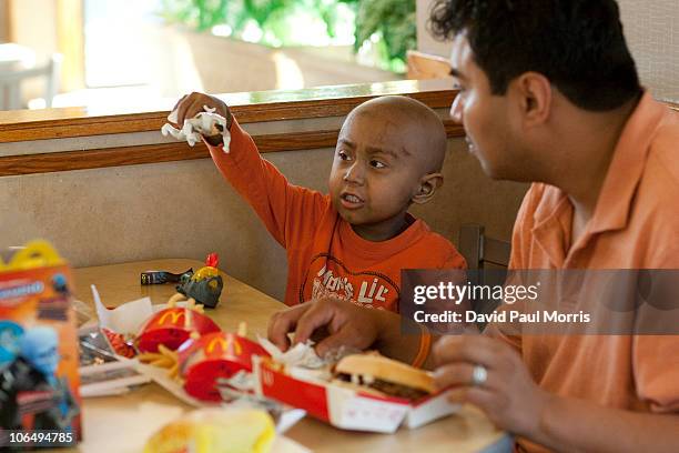 Five-year-old Andy Villatoro plays with a toy he received after ordering a Happy Meal at McDonald's as his father Carlos Villatoro watches on...