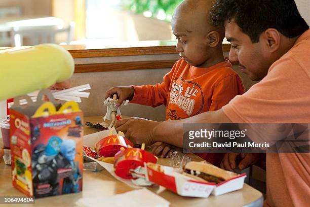 Five-year-old Andy Villatoro plays with a toy he received after ordering a Happy Meal at McDonald's as his father Carlos Villatoro watches on...