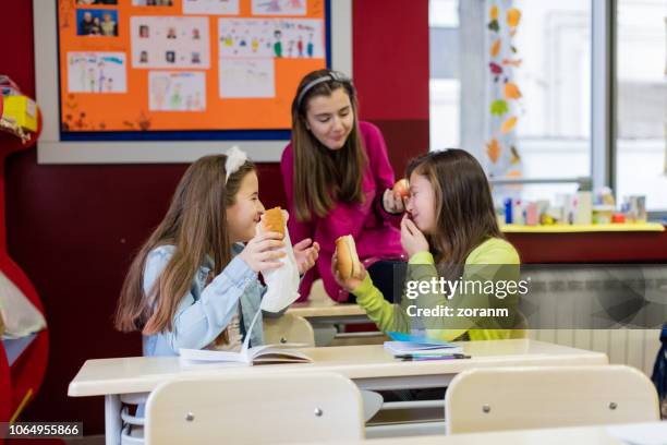 condividere il pranzo durante le vacanze scolastiche - girls laughing eating sandwich foto e immagini stock