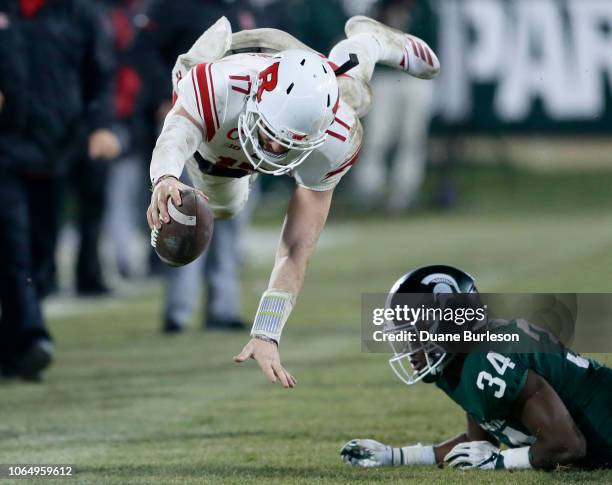 Quarterback Giovanni Rescigno of the Rutgers Scarlet Knights dives over linebacker Antjuan Simmons of the Michigan State Spartans while carrying the...