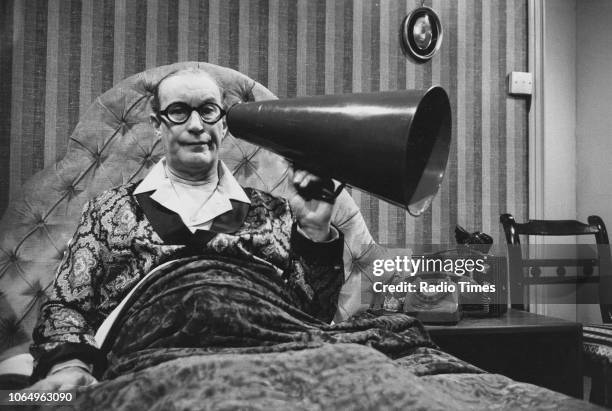 Actor Richard Wattis sitting in bed with a bullhorn in a scene from the television sitcom 'Sykes', January 2nd 1972.