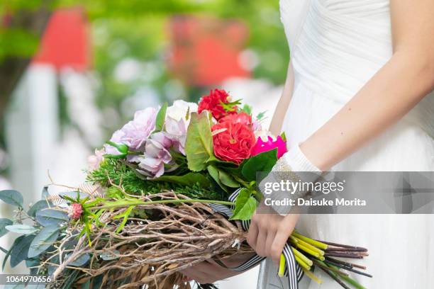 bride holding bouquet of flowers outdoors - 結婚式 日本 ストックフォトと画像