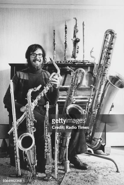 Portrait of musician and composer John Williams with a collection of brass instruments, circa 1965.