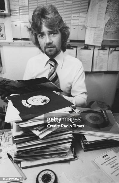 Portrait of television presenter Noel Edmonds with a pile of records, October 1978.