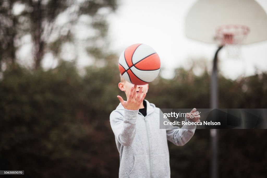 Pre-teen boy spinning basketball on fingertip