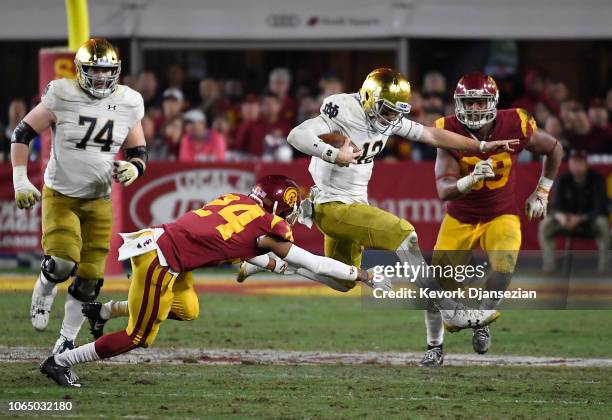 Quarterback Ian Book of the Notre Dame Fighting Irish eludes a tackle by Isaiah Langley of the USC Trojans during the second half at Los Angeles...