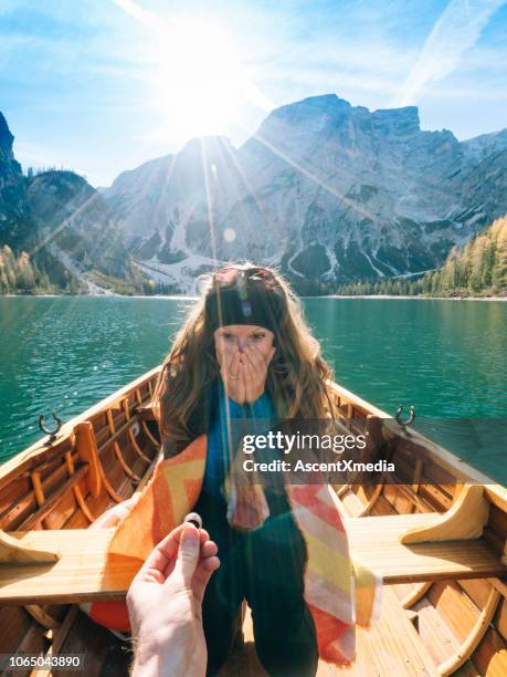 view past man's hand holding ring to woman - engagement stock pictures, royalty-free photos & images