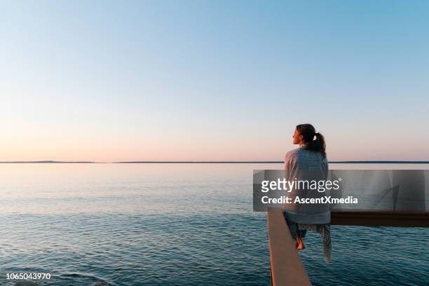 jeune femme assise sur le bord donne à voir - mer photos et images de collection