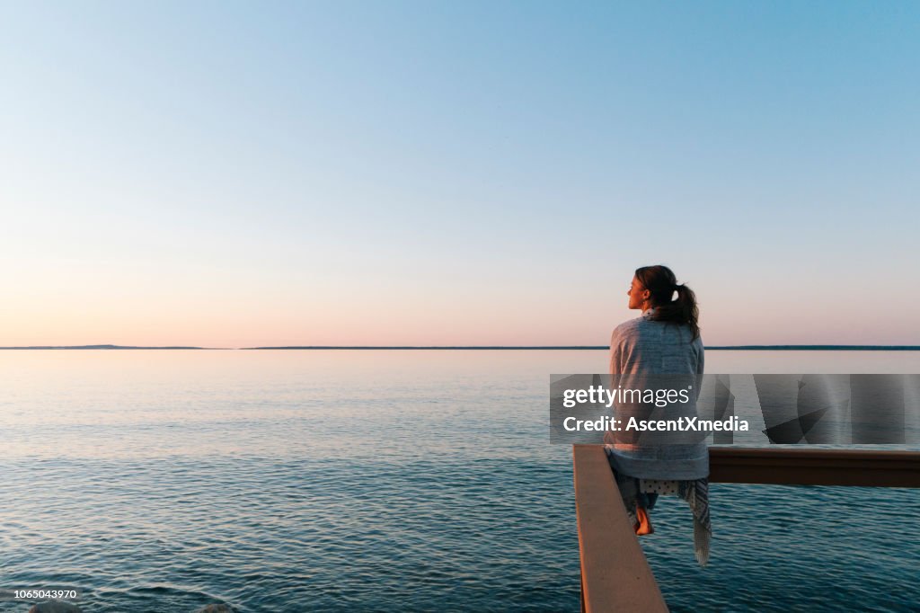 Giovane donna seduta sul bordo guarda fuori dalla vista