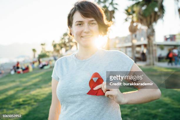 young woman with red aids awareness ribbon - hiv stock pictures, royalty-free photos & images