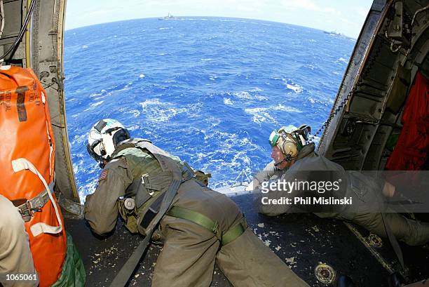 Helicopter crew chief Randall Elkins monitors a landing aboard the USS Port Royal during the RIMPAC excercise operations July 11, 2002 near Oahu,...