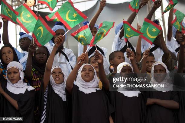 Children sing and hold Mauritanian flags during the launch of the Old Cities Festival of Oualataz, in Oualata, on November 20, 2018. - The Old Cities...