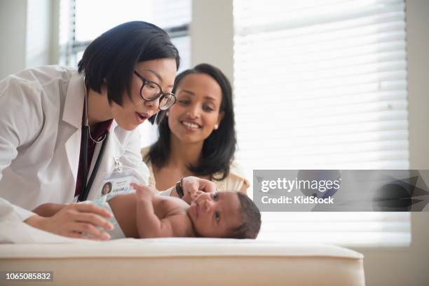 pediatrician examines baby during well check appointment - examining newborn stock pictures, royalty-free photos & images