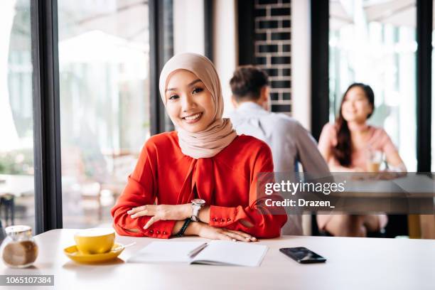 pensive woman drinking coffee in nice bar - hijab stock pictures, royalty-free photos & images