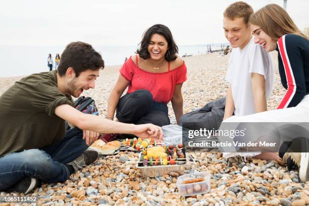 young man prepares the food on barbecue while friends watch and talk. - disposable bbq stock pictures, royalty-free photos & images