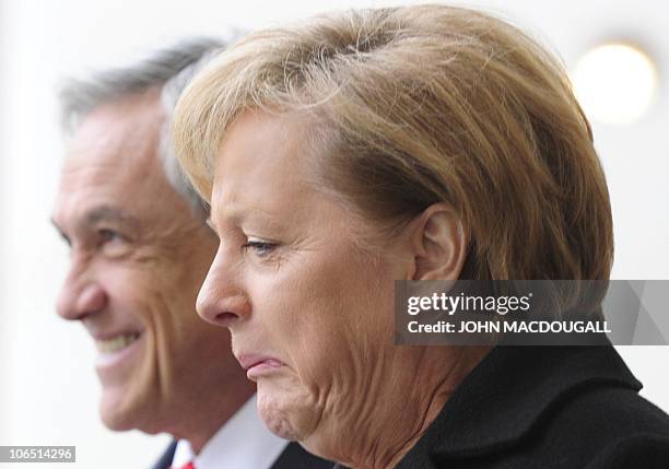 German Chancellor Angela Merkel grimaces as she walks with Chilean President Sebastian Pinera during a welcoming ceremony at the chancellery in...