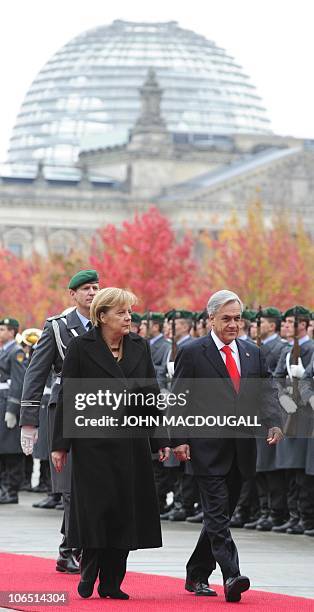 German Chancellor Angela Merkel and Chilean President Sebastian Pinera review an honour guard during a welcoming ceremony at the chancellery in...