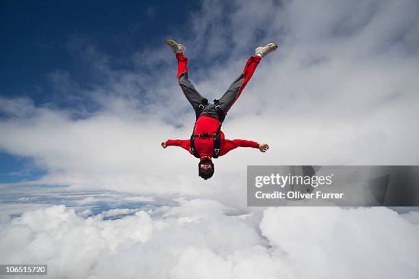 man is flying head down between clouds in the sky. - skydiving photos et images de collection