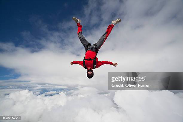 man is flying head down between clouds in the sky. - skydive stock pictures, royalty-free photos & images
