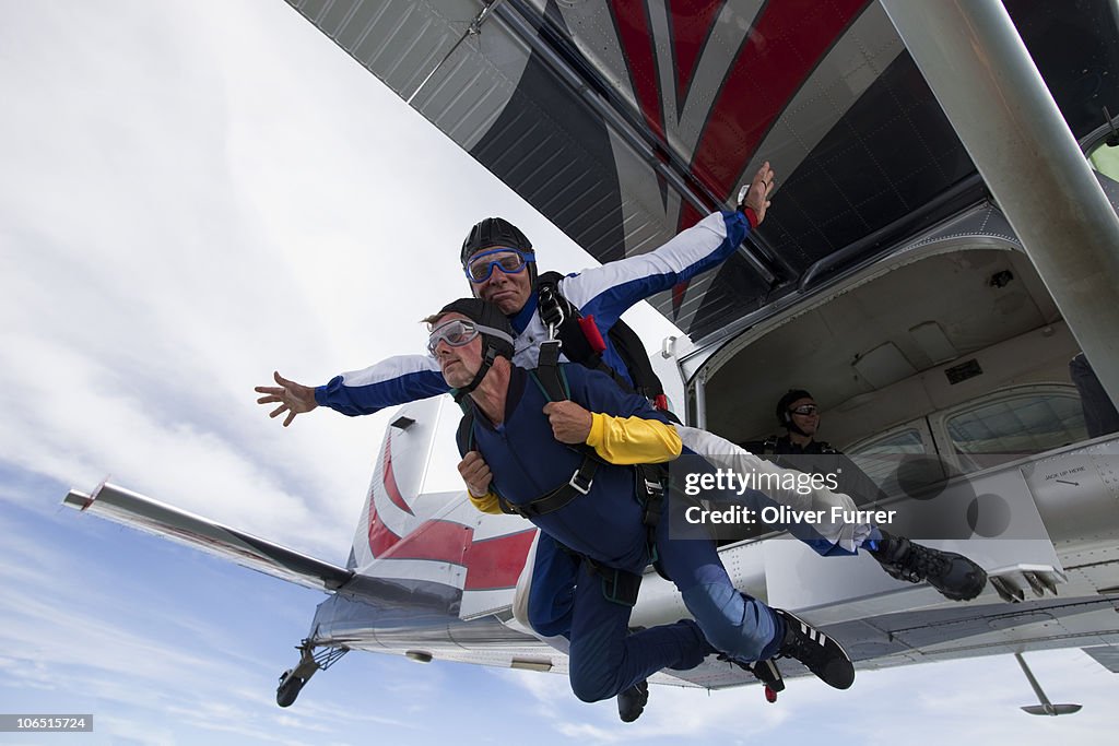 Tandem skydive couple jumping out of the plane.