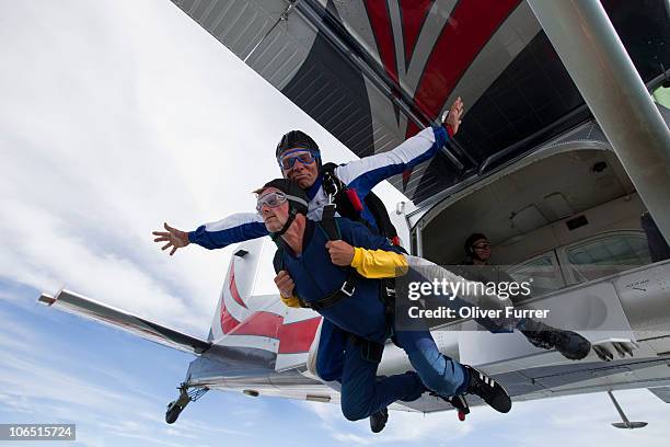 tandem skydive couple jumping out of the plane. - skydiving stockfoto's en -beelden