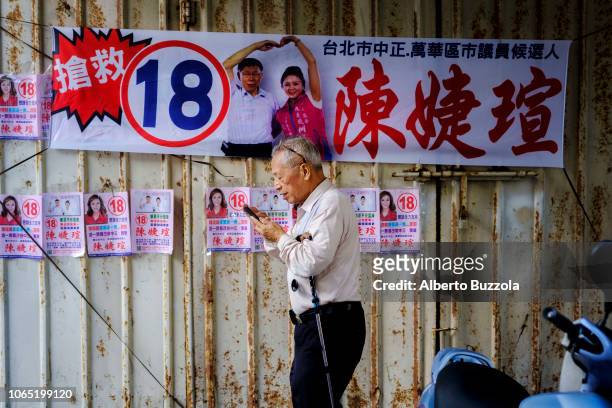 An elder man walks by an election banners, in Wuan Hua District in Taipei, that depicts incumbent and just re elected mayor Ko Wen-je in a fierce...