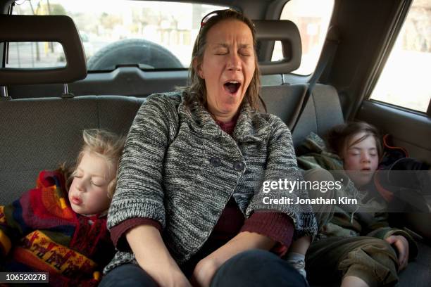 exhausted mother yawns while her daughters sleep. - yawning woman stockfoto's en -beelden