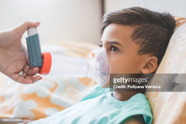 mujer con hijo haciendo inhalación con nebulizador en casa - nebulizador fotografías e imágenes de stock
