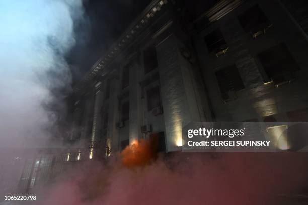 Smoke from a flare thrown by protesters is seen in front of the Russian Embassy in Kiev late on November 25 during a rally following an incident in...