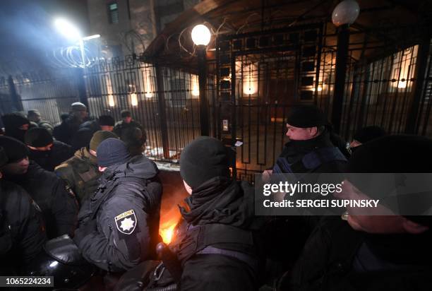 Policemen and servicemen of Ukrainian National Guard extinguish a flare thrown by protesters in front of the Russian embassy in Kiev late on November...