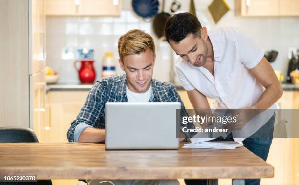 gay couple paying bills online at home - gay couple new house stock pictures, royalty-free photos & images