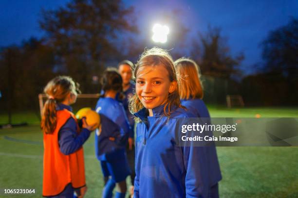 portrait smiling, confident girl soccer player on field at night - flutlicht stock-fotos und bilder