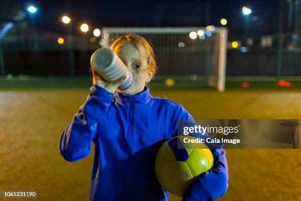 Girl soccer player taking a break, drinking water on field at night