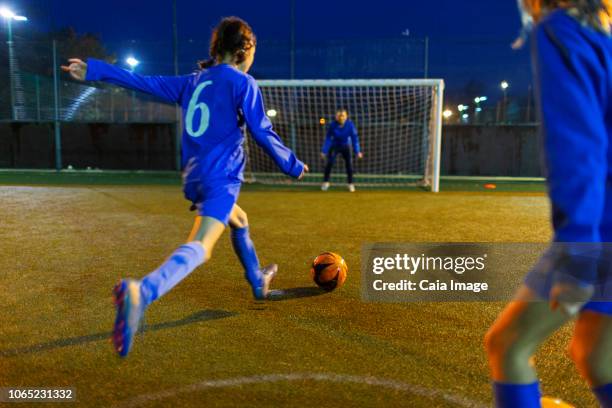 girl soccer player kicking ball toward goal - sport coach united kingdom stock pictures, royalty-free photos & images