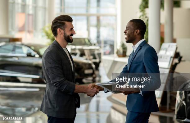 customer closing a deal with a salesman at a car dealership - car dealership imagens e fotografias de stock
