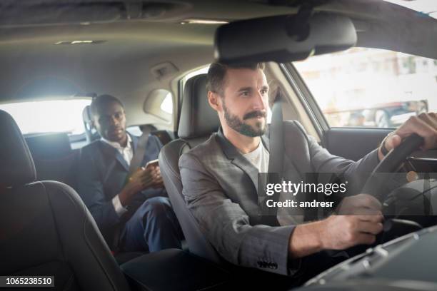 man driving a businessman in a car - chauffeur stock pictures, royalty-free photos & images
