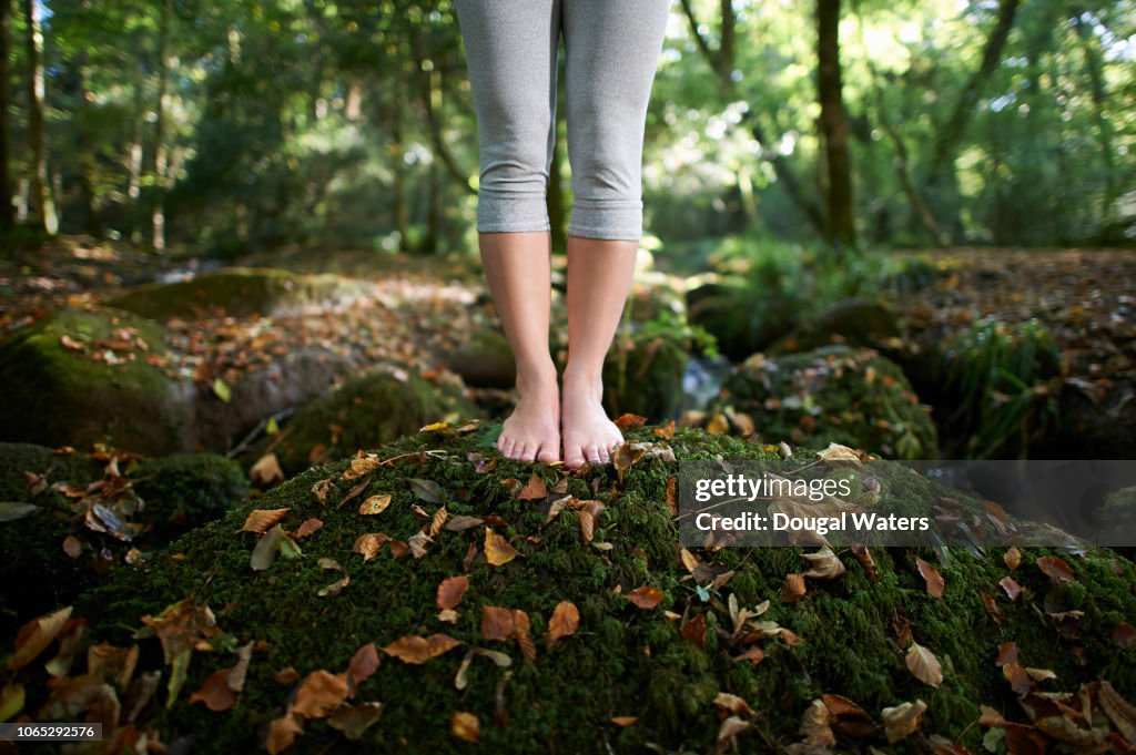 Feet on moss covered rock in autumn woodland.