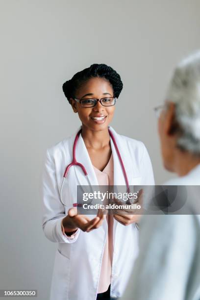 young female doctor explaining senior patient - general practitioner imagens e fotografias de stock