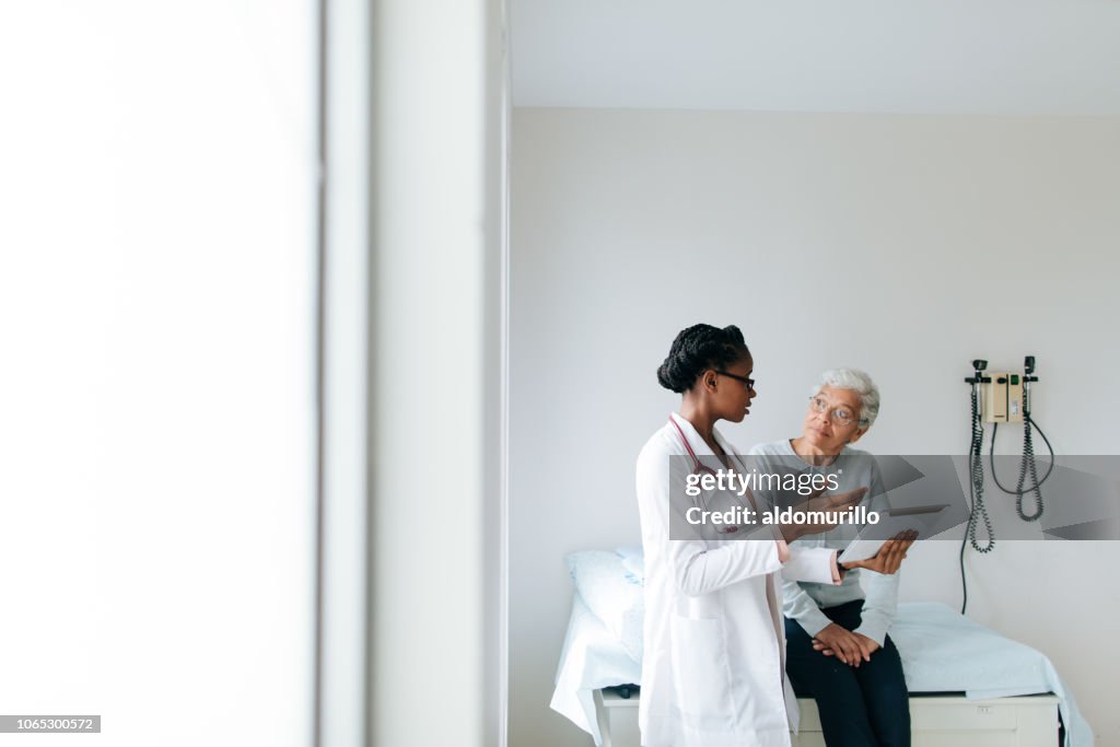 Young female doctor explaining patient with digital tablet