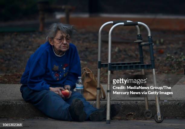 Juanita McLish sits on a curb after she and her husband lost their home in the Campfire blaze raging through Paradise, Calif., Thursday, November 8,...