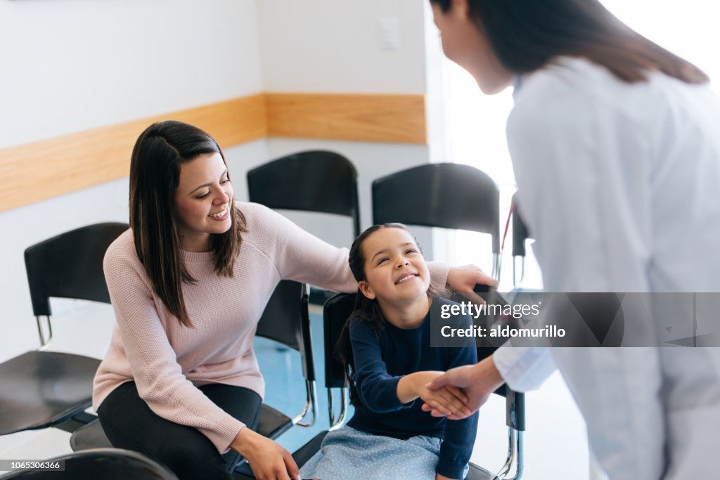 Femme médecin, serrant la main de la jeune fille dans la salle d’attente