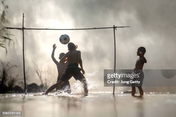 group of children playing a football on nature river at thailand - poor kids playing soccer stock pictures, royalty-free photos & images