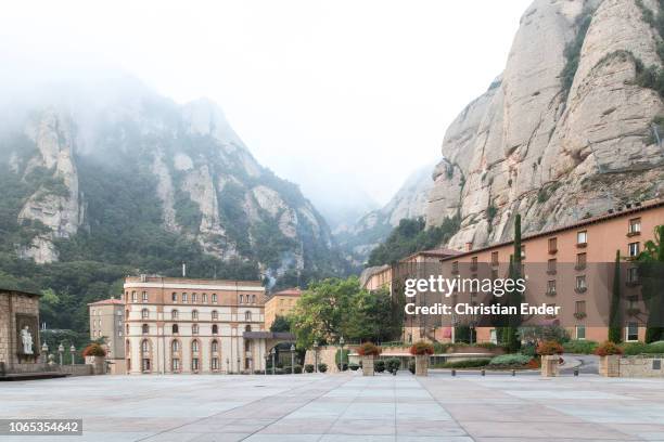 Spain, Montserrat Abbey Montserrat at the sqaure in front of it with view at Roca de St. Jaume covered in fog and clouds and some historical and more...