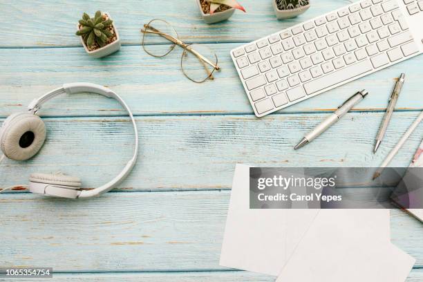 woman home office desk workspace with laptop, headphones  cactus in pastel blue wooden. flat lay, top view. stylish female concept - office desk top view stockfoto's en -beelden