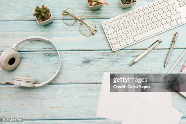 woman home office desk workspace with laptop, headphones  cactus in pastel blue wooden. flat lay, top view. stylish female concept - office table top stock pictures, royalty-free photos & images