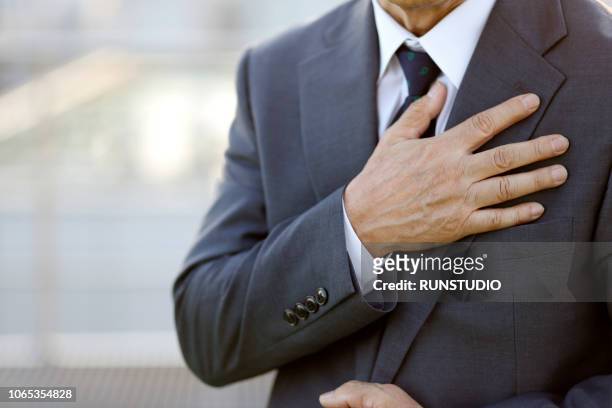 close-up of senior businessman with hand on chest - main sur la poitrine photos et images de collection