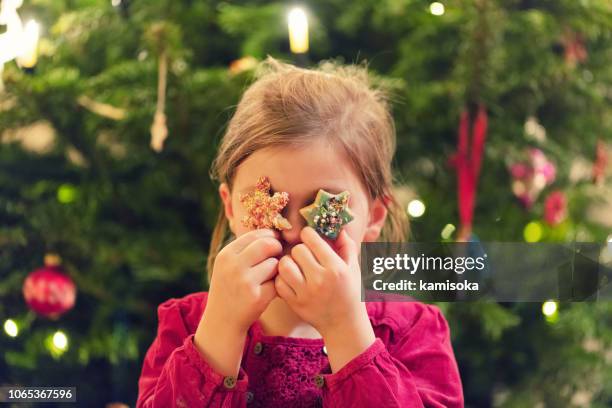 mädchen hält sterne cookies vor ihren augen in der weihnachtszeit - hand gag stock-fotos und bilder