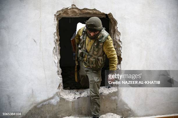Turkey backed Syrian rebel-fighter walks through a hole in a wall while on patrol near the city of al-Bab in Aleppo province on the border with...