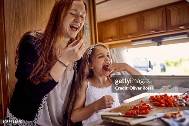 girl with elder sister tasting vegetables in caravan kitchen - generationen kochen stock-fotos und bilder