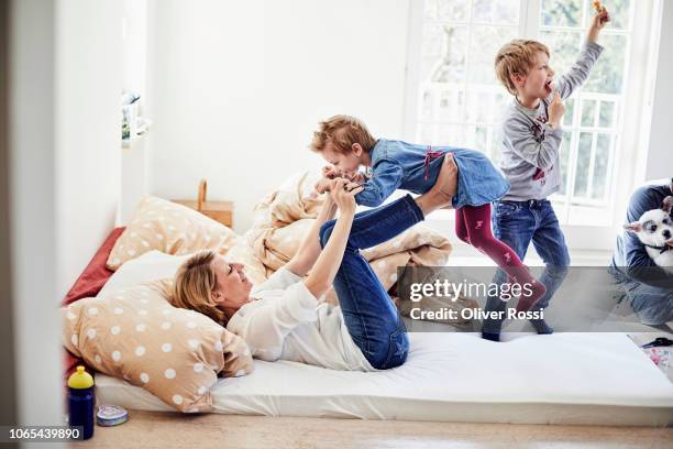 mother and children romping around in bed - één ouder stockfoto's en -beelden